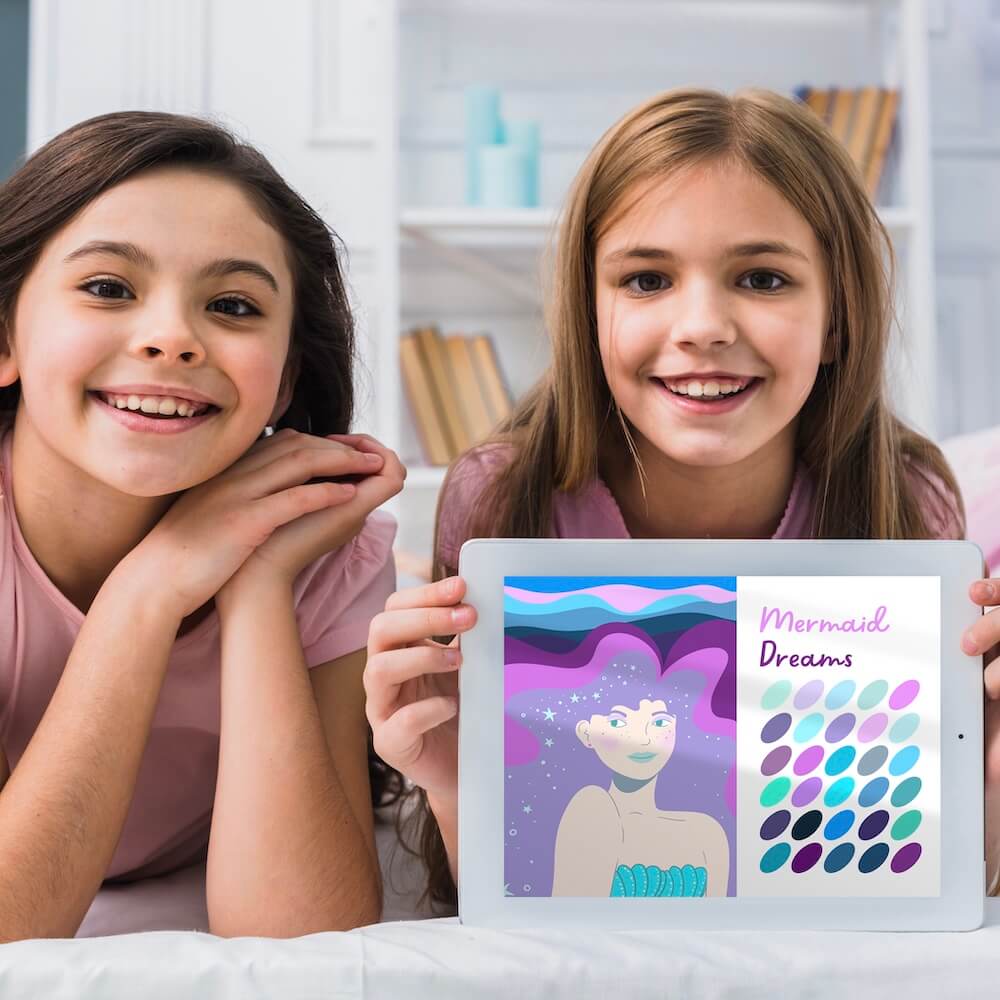 two girls holding iPad with mermaid Procreate colour palette and illustration